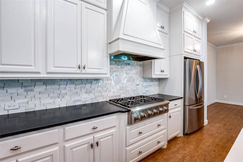 Designed to make cooking & entertaining a pleasure, this gorgeous kitchen features a gas cooktop, statement vent hood & detailed tile backsplash.