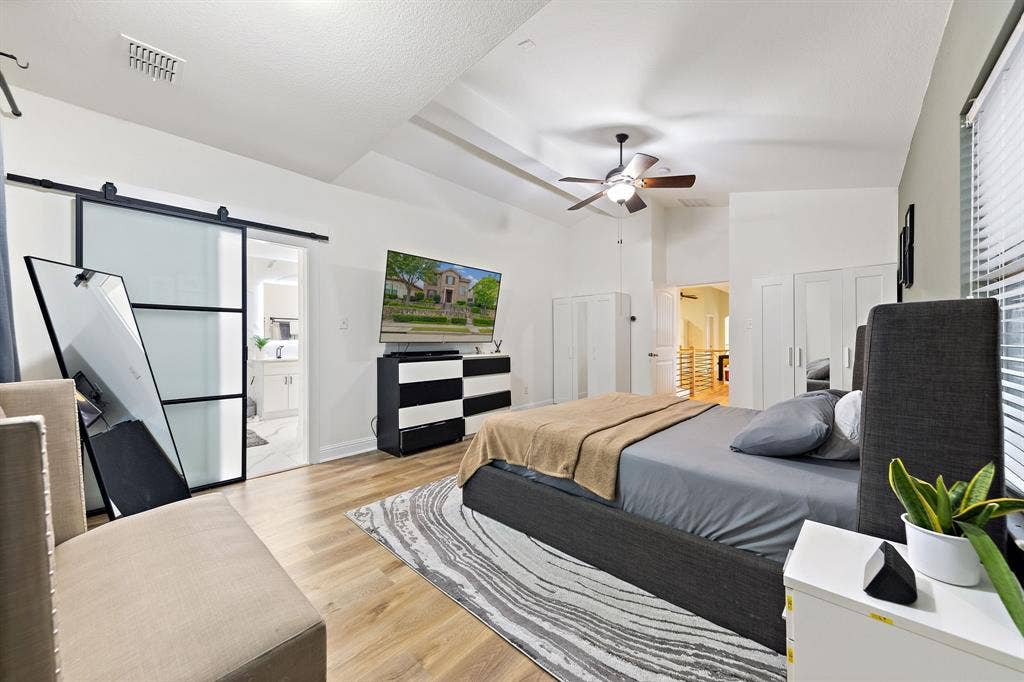 7011 Nueces Drive, Irving, TX 75039 Vaulted ceiling with ceiling fan, wood-finish flooring, sliding barn door with frosted panels, and built-in cabinetry