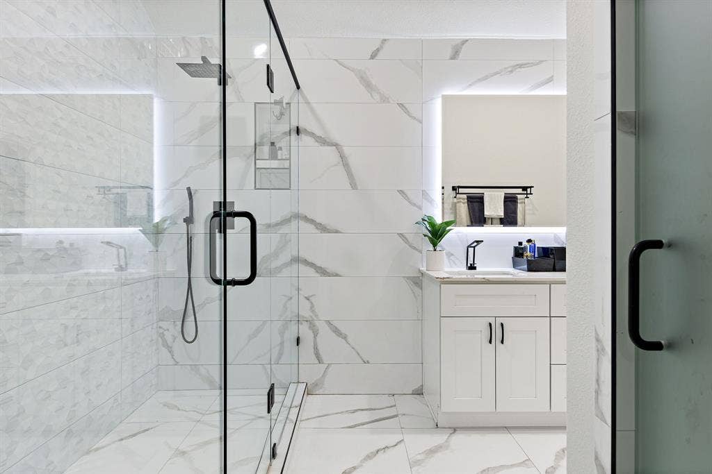 7011 Nueces Drive, Irving, TX 75039 Glass-enclosed shower with a rainfall showerhead and a built-in recessed shelf