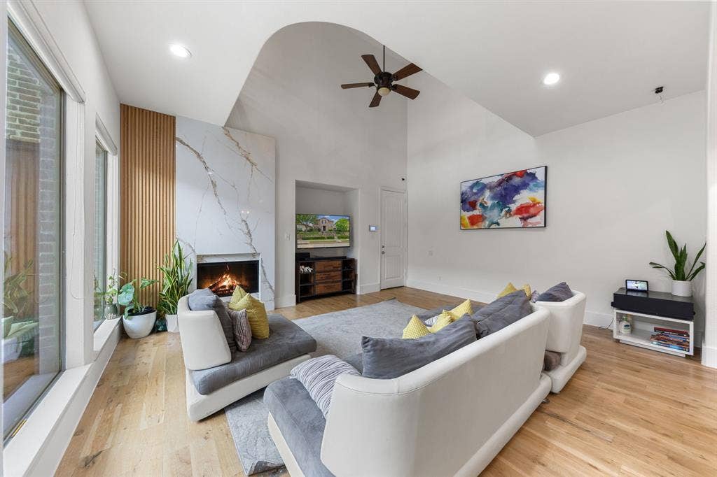 7011 Nueces Drive, Irving, TX 75039 Vaulted ceiling with recessed lighting, wood-finish flooring, full-height stone fireplace, wood slat accent wall, and expansive window