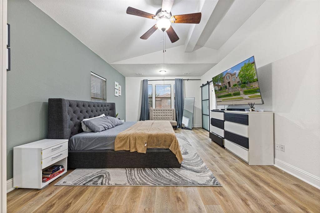 7011 Nueces Drive, Irving, TX 75039 Vaulted ceiling with a ceiling fan, light wood-finish flooring, and a sliding barn door