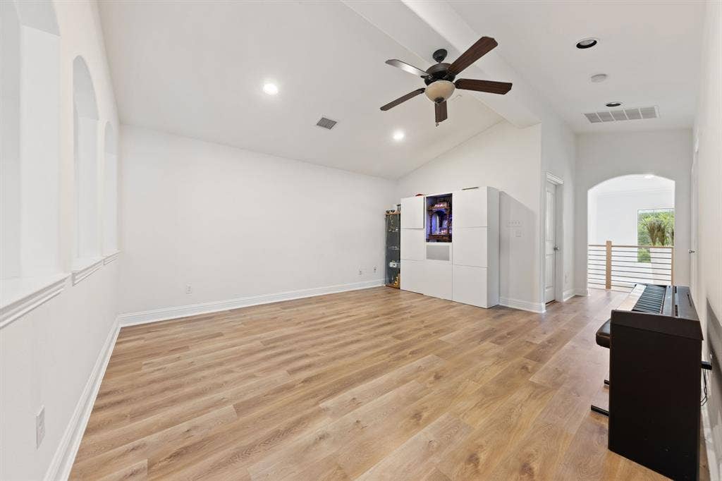 7011 Nueces Drive, Irving, TX 75039 Vaulted ceiling with a ceiling fan, recessed lighting, wood-finish flooring, and arched window details