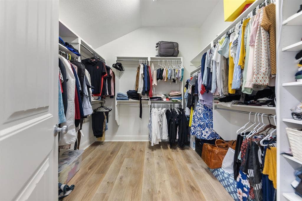 7011 Nueces Drive, Irving, TX 75039 Walk-in closet featuring wood-finish flooring, white shelving, and multiple clothing rods
