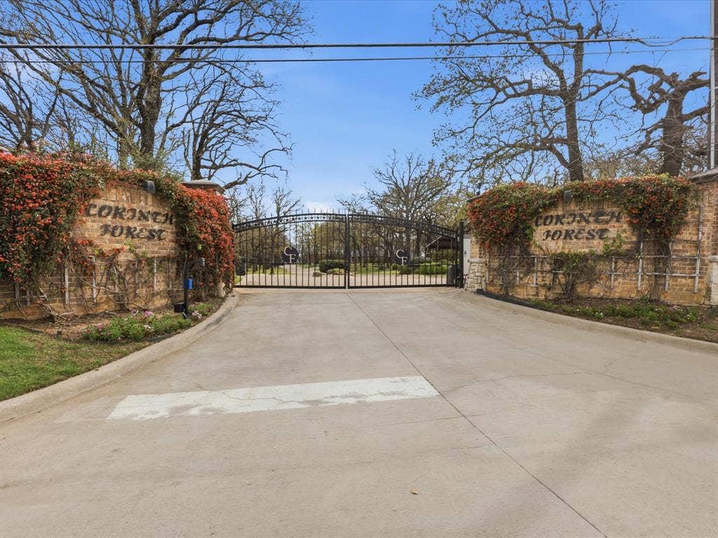 Private gated communityImpressive gated entry featuring substantial brick pillars with ivy-covered stonework and decorative wrought-iron gates