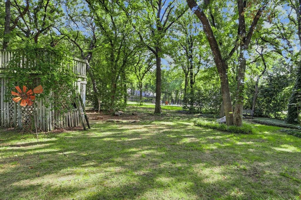 Expansive grassy yard with mature trees and wood fencing