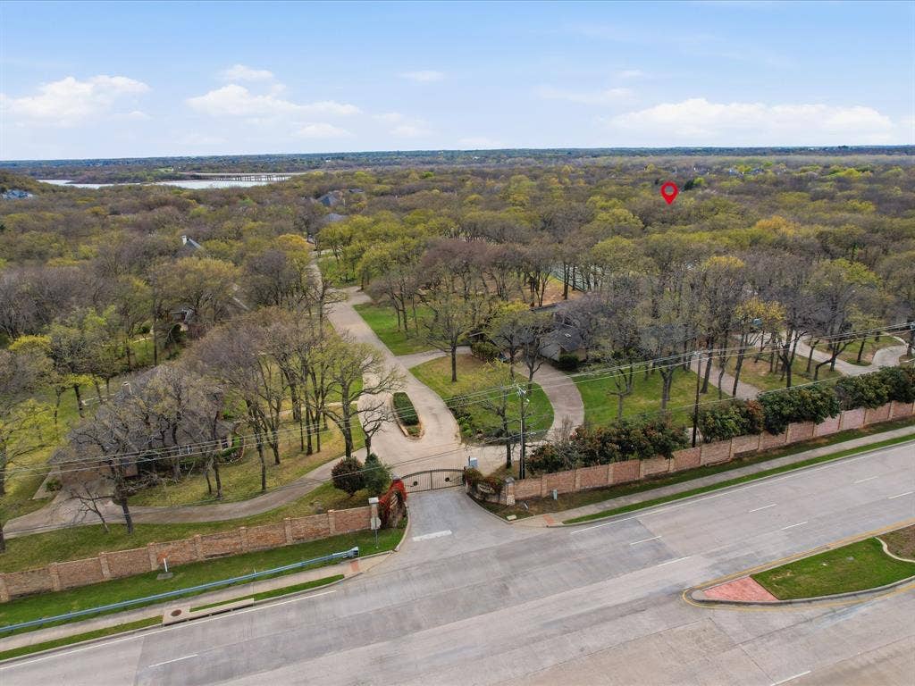 Expansive forested area with a visible body of water, paved roads, and brick perimeter walls
