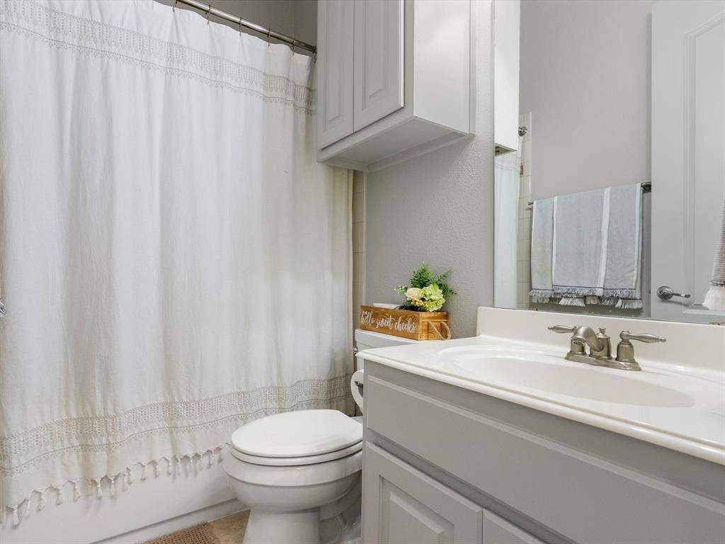 First-level full bathroom with shower/tub combo and storage cabinets