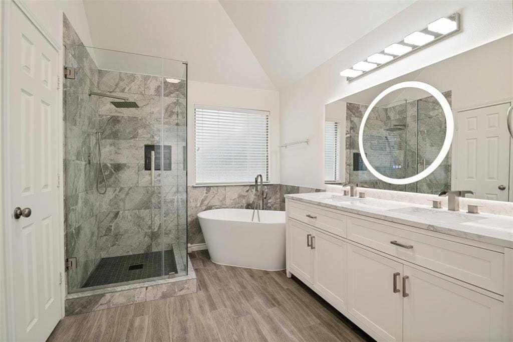 1516 Cedar Grove Court, Allen, TX 75002 Spacious bathroom featuring a frameless glass shower enclosure, freestanding soaking tub, dual vanity with undermount sinks, and wood-finish flooring