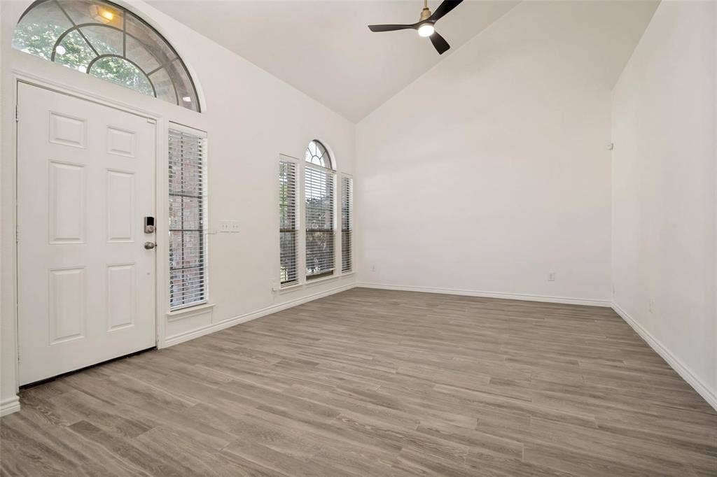 1516 Cedar Grove Court, Allen, TX 75002 Vaulted ceiling with a black ceiling fan, wood-finish flooring, white panel door, and arched transom windows