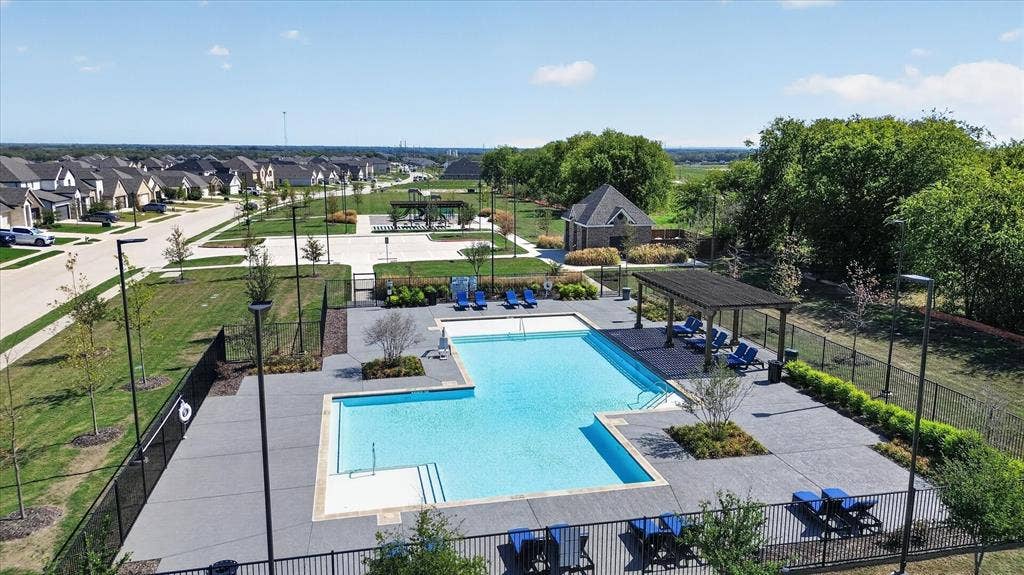 Community swimming pool with an integrated spa, expansive surrounding concrete decking, and an adjacent covered pergola