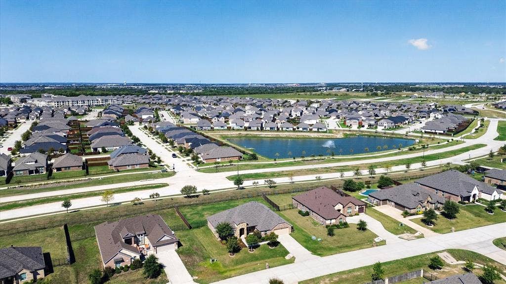 Aerial depiction of a residential development featuring single-family homes, paved streets, and an artificial pond with a water feature