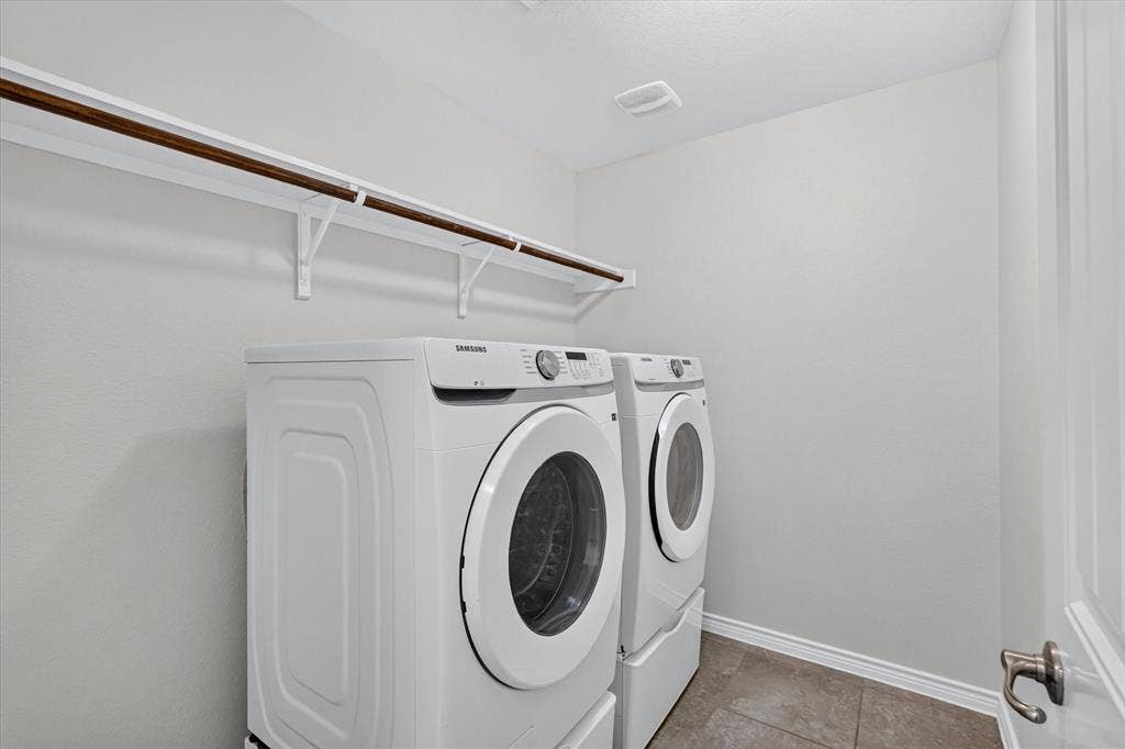 Laundry area featuring a hanging rod, wall-mounted brackets, and tile flooring