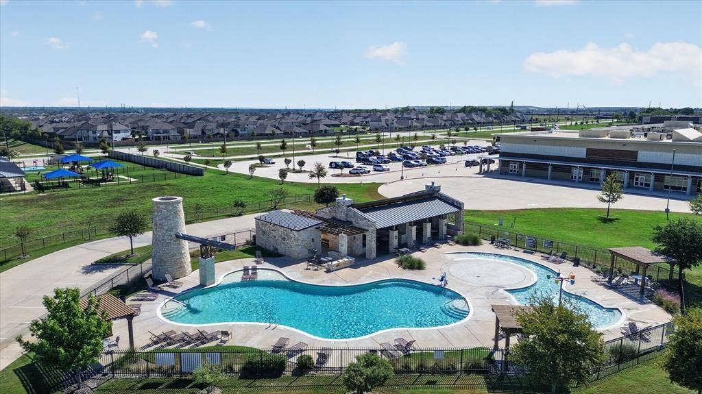 Community swimming pool, stone-clad pool house, separate wading pool, lounge seating, and surrounding green spaces