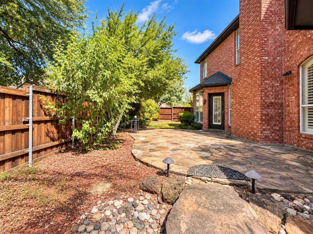2912 Meadow Glen Drive, Flower Mound, TX 75022 Brick exterior with a covered entry, flagstone patio, and mature trees