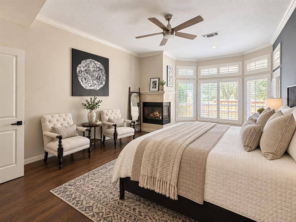 2912 Meadow Glen Drive, Flower Mound, TX 75022 Hardwood-finish flooring, crown molding, bay windows with plantation shutters, corner fireplace with stone surround, and a ceiling fan with integrated lighting