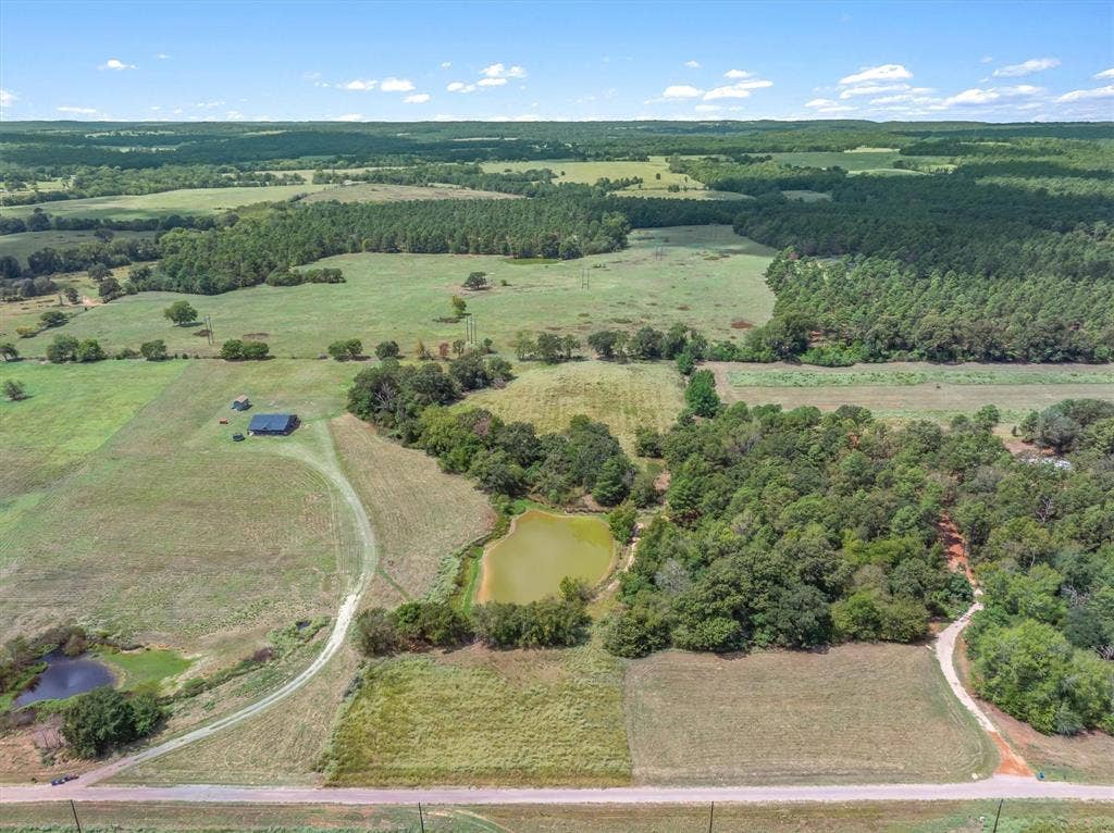 24619 Private Road 8102, Frankston, TX 75763 Expansive rural landscape featuring a single-story structure, two ponds, mature tree lines, and open fields