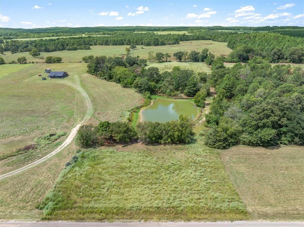 24619 Private Road 8102, Frankston, TX 75763 Expansive rural property featuring an established structure, a visible pond, and abundant mature trees