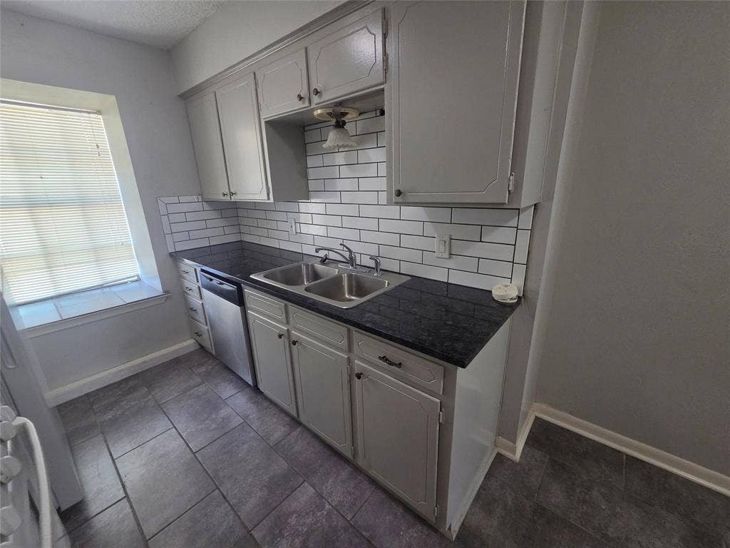 1717 N Locust Street, #6, Denton, TX 76201 Kitchen featuring white cabinetry, dark countertops, a subway tile backsplash, a stainless steel dishwasher, and tile flooring