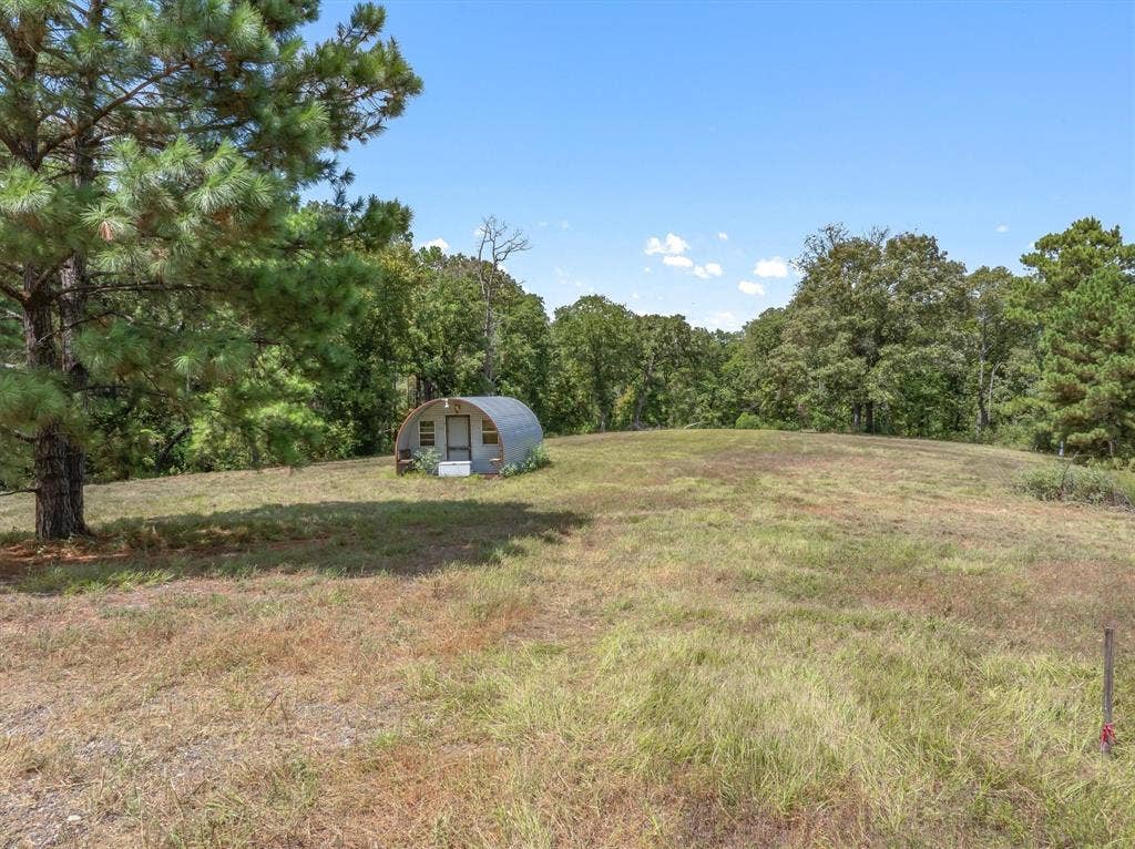 24670 Private Road 8102, Frankston, TX 75763 Expansive natural landscape with mature trees and a metal quonset hut structure