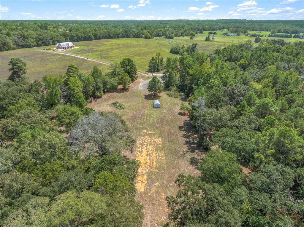 24670 Private Road 8102, Frankston, TX 75763 Expansive property featuring wooded areas, open fields, a detached structure, and a main residence with an attached garage