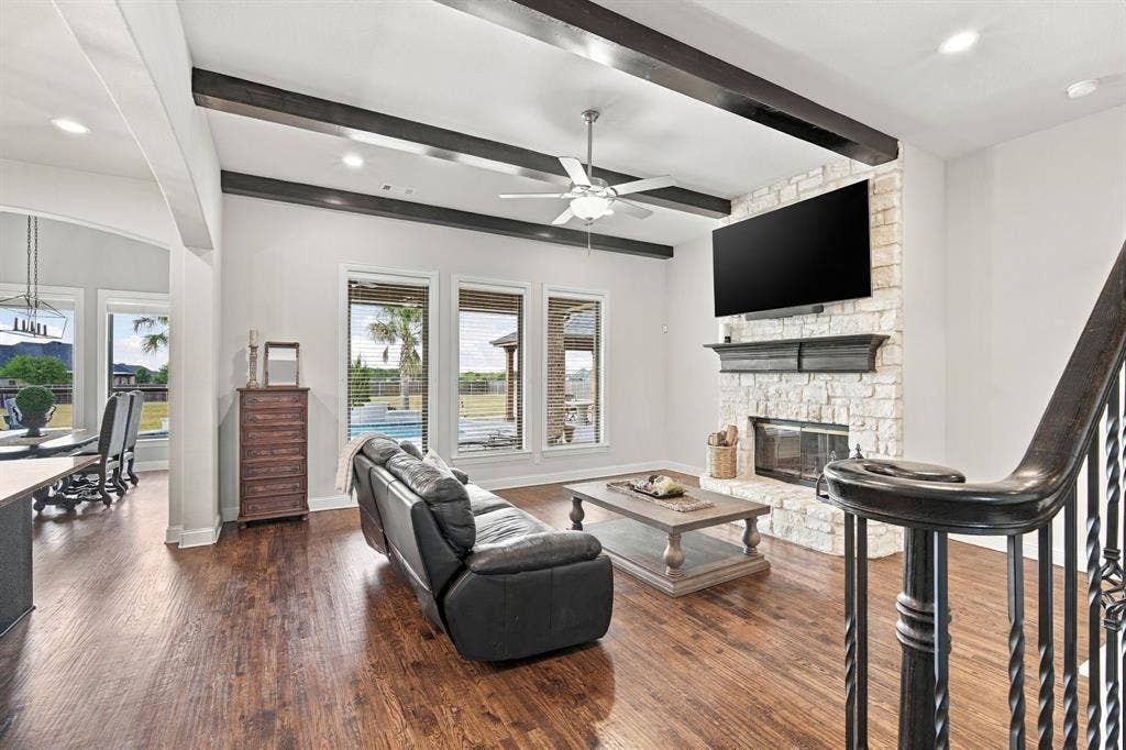 5620 Limestone Lane, Midlothian, TX 76065 High ceilings with wood beams, a stone fireplace, and a gorgeous view in this sunny living room.