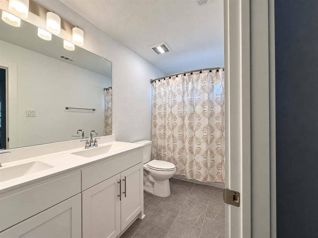 1411 Potenza Road, Fate, TX 75087 Dual basin vanity with white cabinetry, polished chrome fixtures, and a large wall-mounted mirror