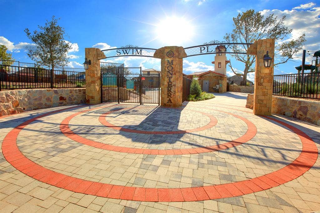 1411 Potenza Road, Fate, TX 75087 Community recreational area featuring stone-clad columns, a decorative metal entrance arch, paved stone pathways, and black metal perimeter fencing