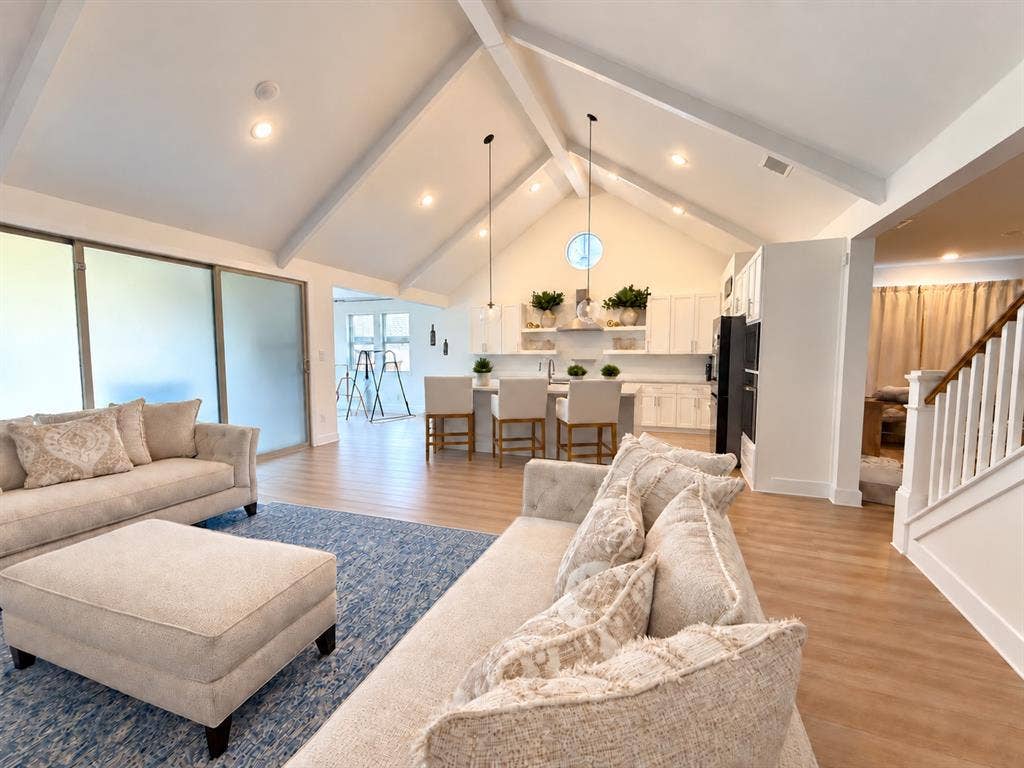 1411 Potenza Road, Fate, TX 75087 Vaulted ceilings with exposed beams, wood-finish flooring, white kitchen cabinetry, a kitchen island with seating, and a modern appliance suite
