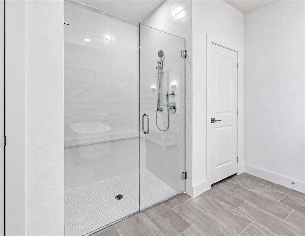 1411 Potenza Road, Fate, TX 75087 Shower with clear glass enclosure, white subway tile walls, built-in bench, and white hexagonal floor tiles