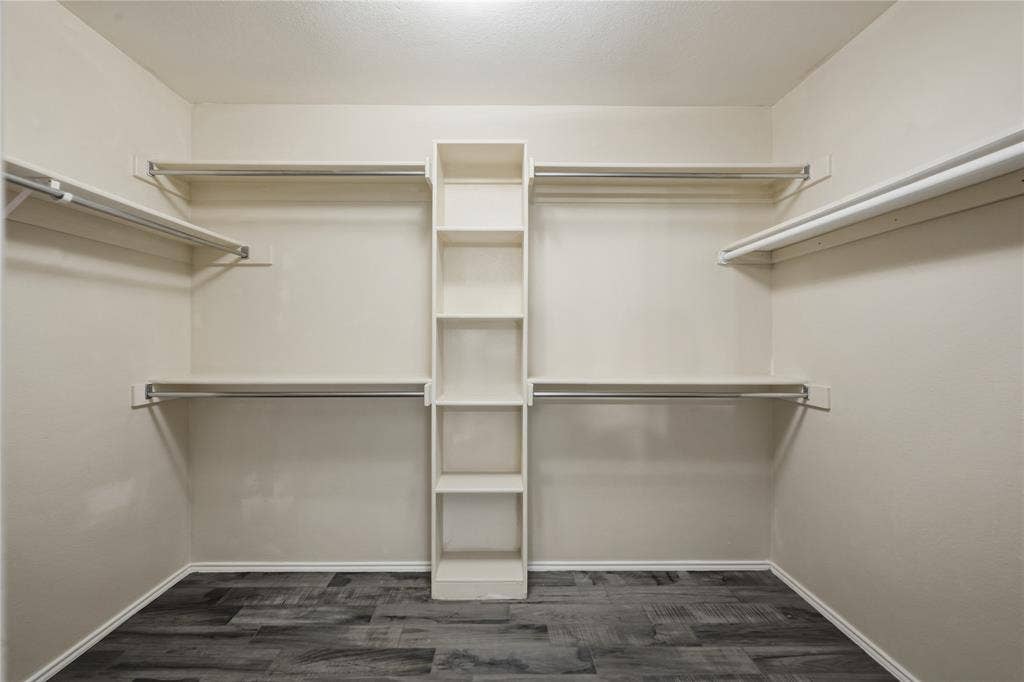 Built-in shelving, multiple hanging rods, and wood-finish flooring
