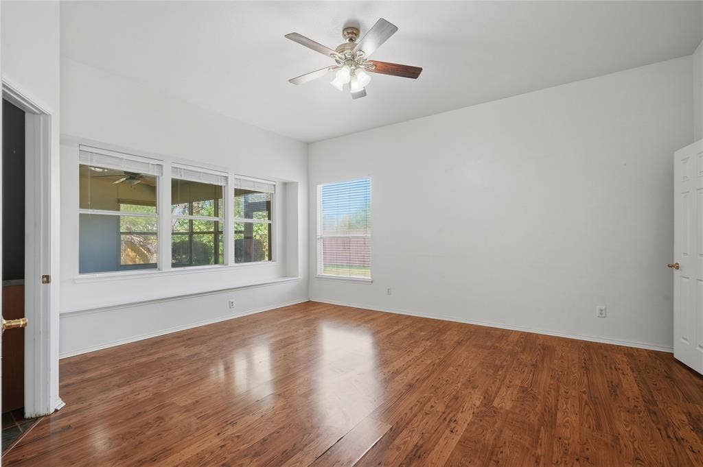 Wood-finish flooring throughout, vaulted ceiling, and a ceiling fan with light fixture