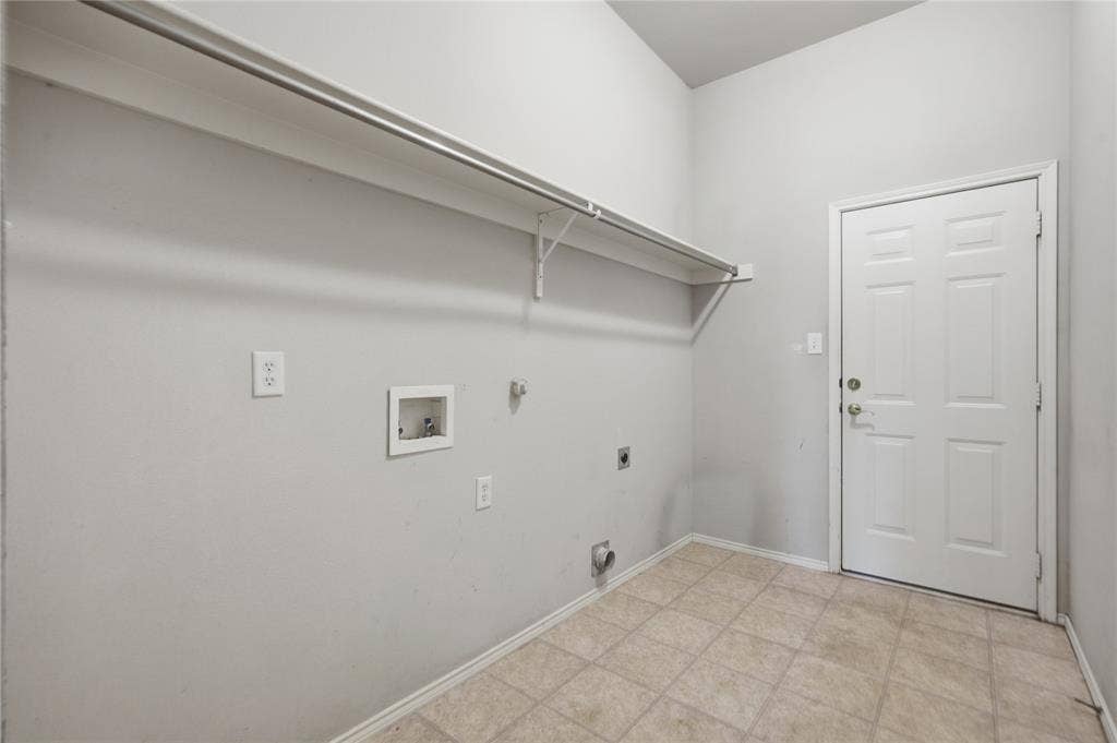 Utility room with tile flooring, wall-mounted shelving, and a paneled entry door