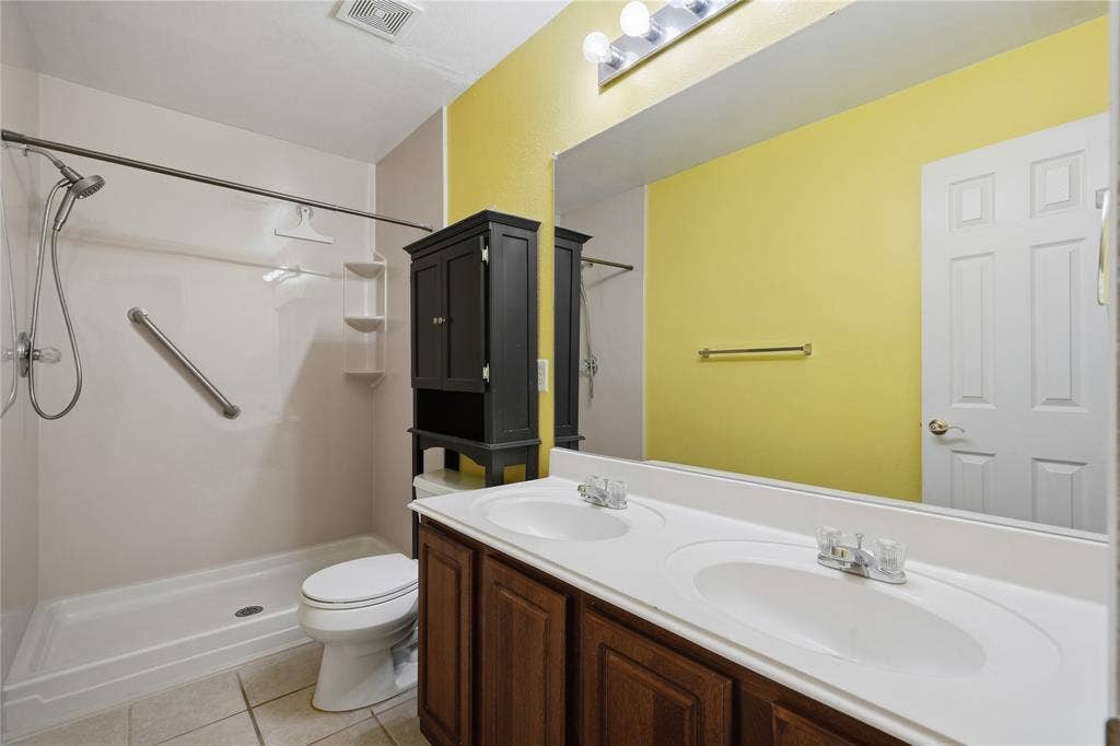 Dual vanity with integrated sinks, wood-finish cabinetry, and a wide mirror