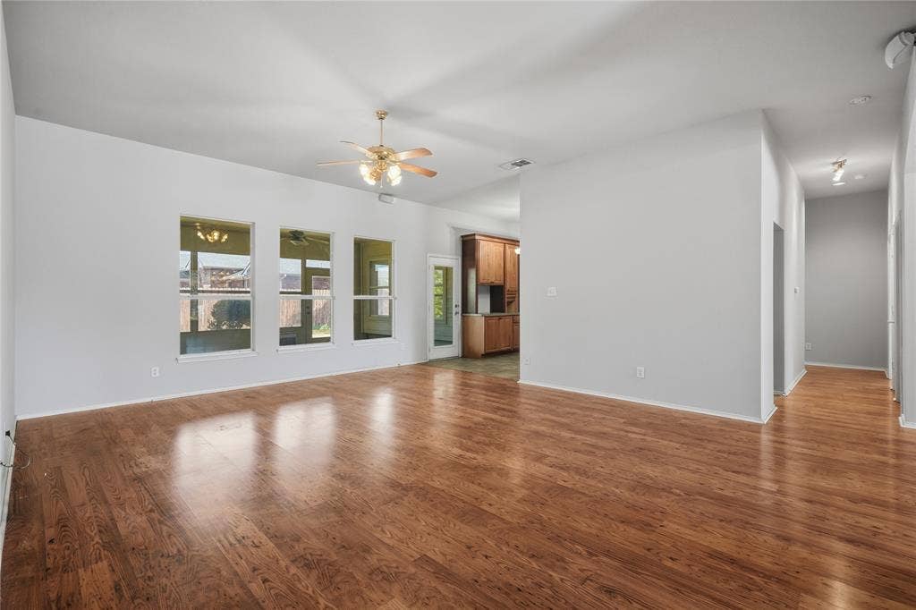Spacious interior with wood-finish flooring, multiple windows, vaulted ceiling, and a ceiling fan