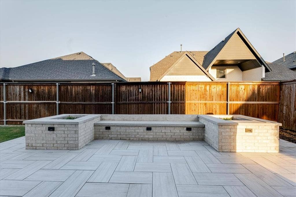 4102 Parkview Boulevard, Celina, TX 75009 Expansive paver patio with a herringbone pattern, featuring a built-in brick seating area with integrated lighting and two planter boxes