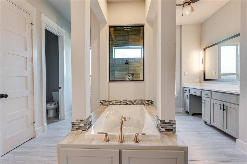 4102 Parkview Boulevard, Celina, TX 75009 Soaking tub with mosaic tile accents, dual vanity with undermount sinks, and a walk-in shower with a transom window