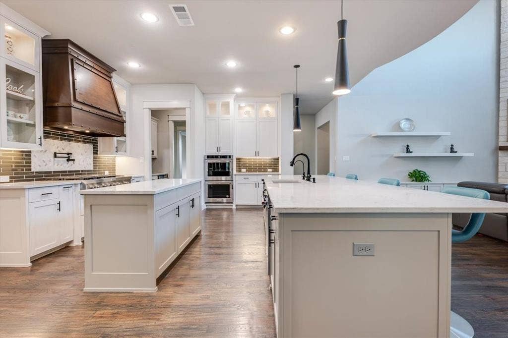 4102 Parkview Boulevard, Celina, TX 75009 Gourmet kitchen featuring white cabinetry, dual islands with light-toned countertops, integrated stainless steel appliances, and wood-finish flooring