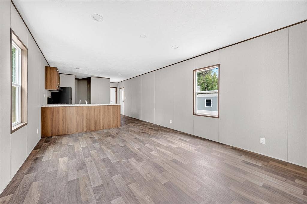 Open-concept room featuring wood-finish flooring, recessed lighting, neutral panel walls, and a wood-finish peninsula counter