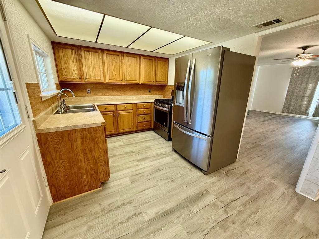 Kitchen featuring wood cabinetry, stainless steel refrigerator, stainless steel range, and wood-finish flooring