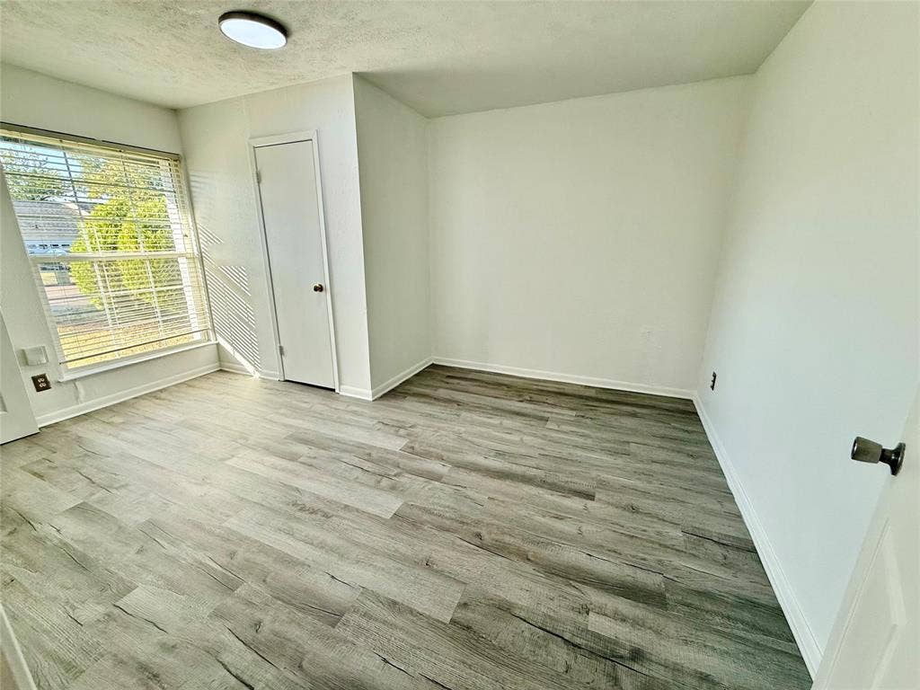 Wood-finish flooring, white walls, and a ceiling-mounted light fixture