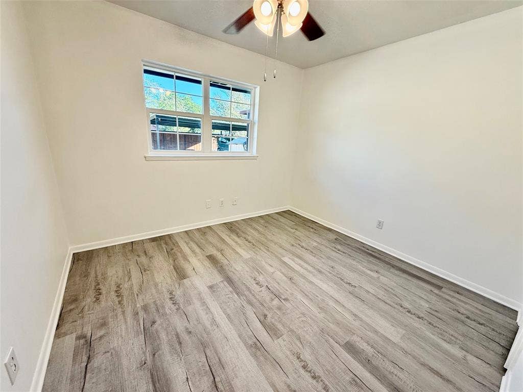 Wood-finish flooring, white walls, and a ceiling fan with integrated lighting