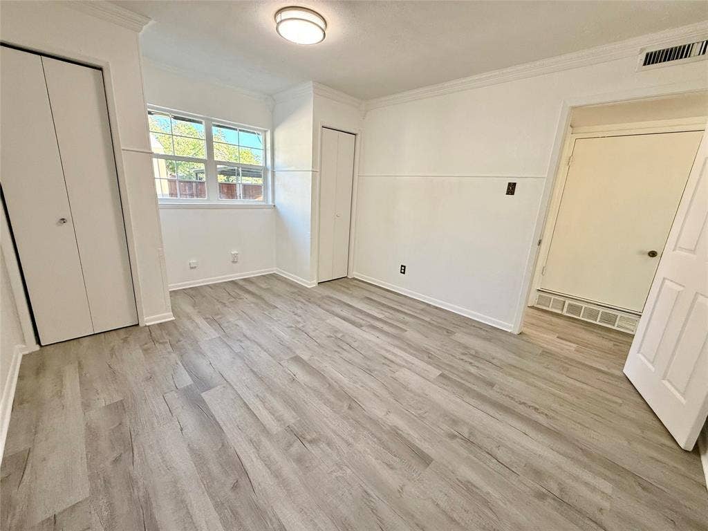 Wood-finish flooring, crown molding, and two bi-fold door closets