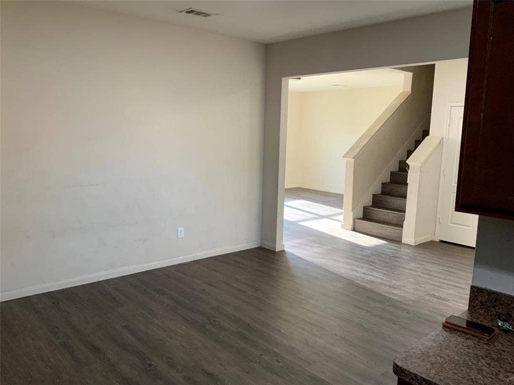 1030 Stanwyck Avenue, Duncanville, TX 75137 Wood-finish flooring throughout, light-toned wall paint, and a built-in staircase with neutral-toned risers