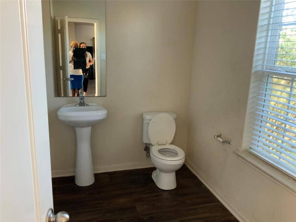 1030 Stanwyck Avenue, Duncanville, TX 75137 Pedestal sink with mirror, toilet, and wood-finish flooring