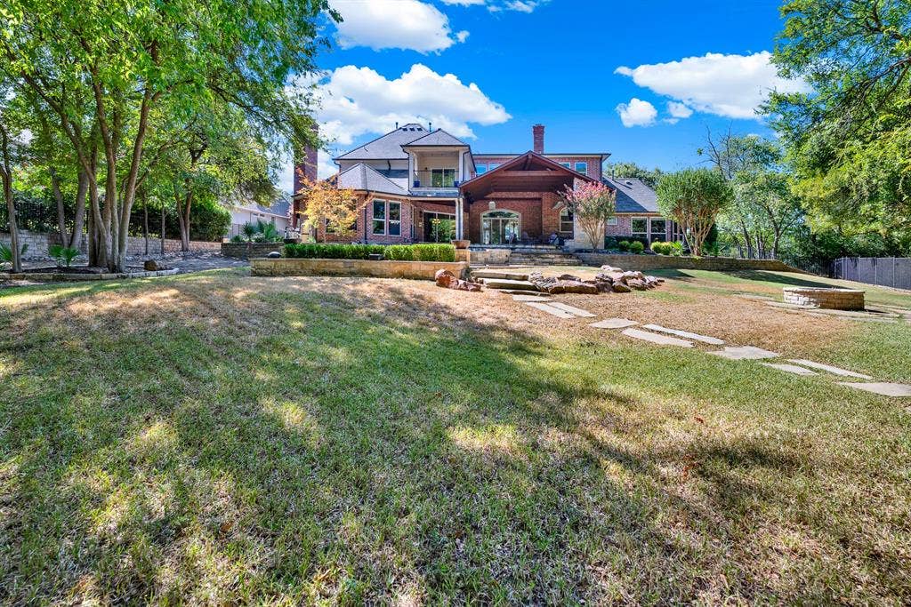 5237 SKY LAKE Drive, Plano, TX 75093 Tiered stone retaining walls step up toward the multi-level brick residence framed by expansive lawn. Imagine kids playing outdoor games across the grass before gathering for dinner on the porch.