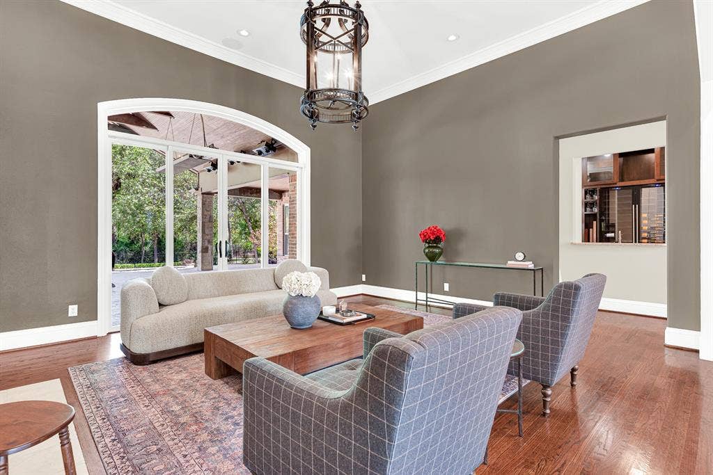 5237 SKY LAKE Drive, Plano, TX 75093 A wide arched glass doorway frames leafy outdoor views, pouring natural light against rich taupe walls. Imagine curling up with a book as soft afternoon light warms the room.