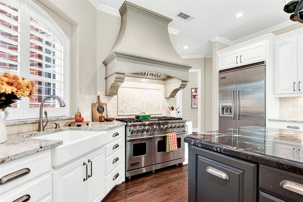 5237 SKY LAKE Drive, Plano, TX 75093 A sculpted hearth-style range hood anchors the cooking alcove, catching bright light from an arched window. Visualize simmering a savory dinner sauce on a cozy weeknight.
