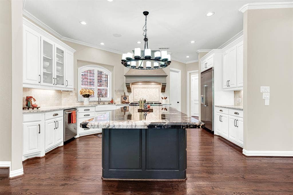 5237 SKY LAKE Drive, Plano, TX 75093 An expansive central island grounds the open kitchen beneath warm, balanced overhead lighting. Picture prepping weekend brunch while family gathers around to chat.