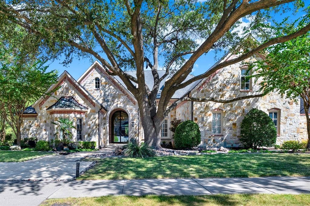 5237 SKY LAKE Drive, Plano, TX 75093 A magnificent mature oak arches over the rustic stone facade, filtering dappled sunlight across the grand entry. Arriving home feels like entering a private, tranquil estate every single afternoon.
