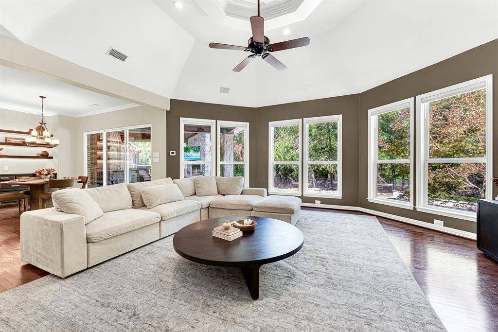 5237 SKY LAKE Drive, Plano, TX 75093 Panoramic bay-style windows frame leafy outdoor views, filling the high-ceilinged room with balanced daylight. Imagine hosting weekend movie nights bathed in the soft glow of dusk outside